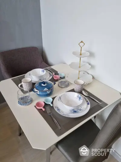 Charming dining setup with elegant tableware and cozy chairs in a modern apartment.