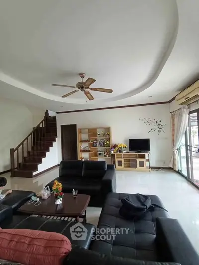 Spacious living room with modern furniture and elegant staircase in a stylish home.