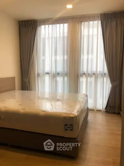 Cozy bedroom with large windows and elegant curtains in modern apartment.