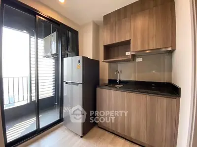 Modern kitchen with sleek cabinets and balcony access, featuring a stainless steel fridge.
