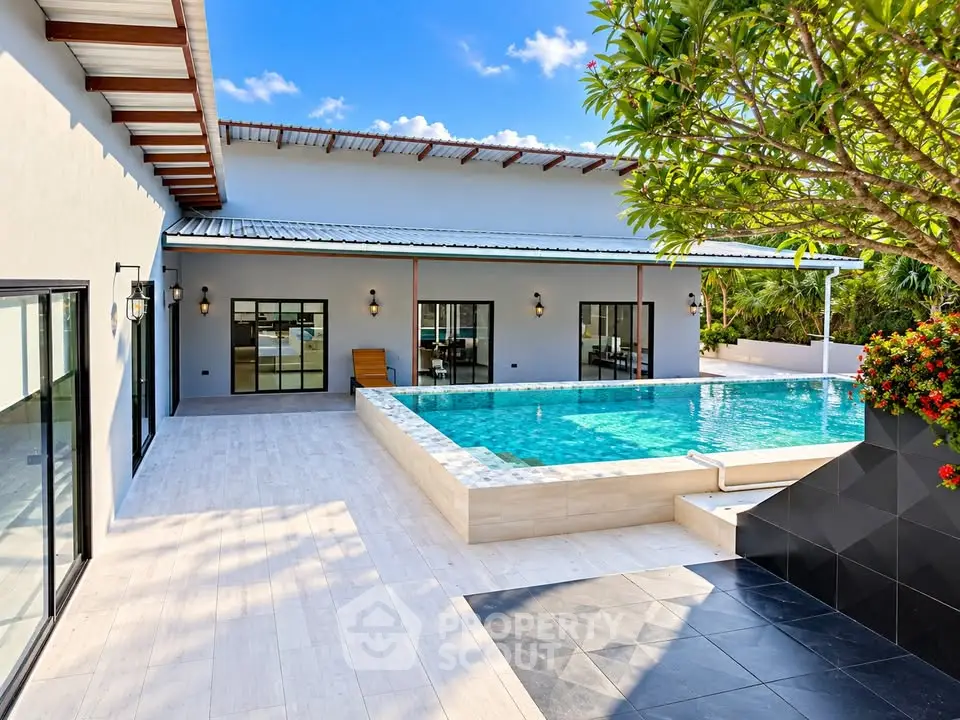 Luxurious modern villa with private pool and spacious patio under clear blue skies.