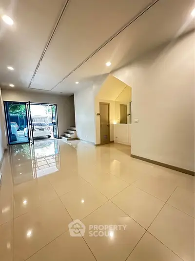 Spacious modern living room with glossy tile flooring and large windows for natural light.