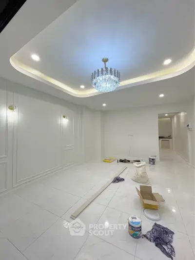 Elegant living room with chandelier and white tiled flooring, showcasing modern interior design.