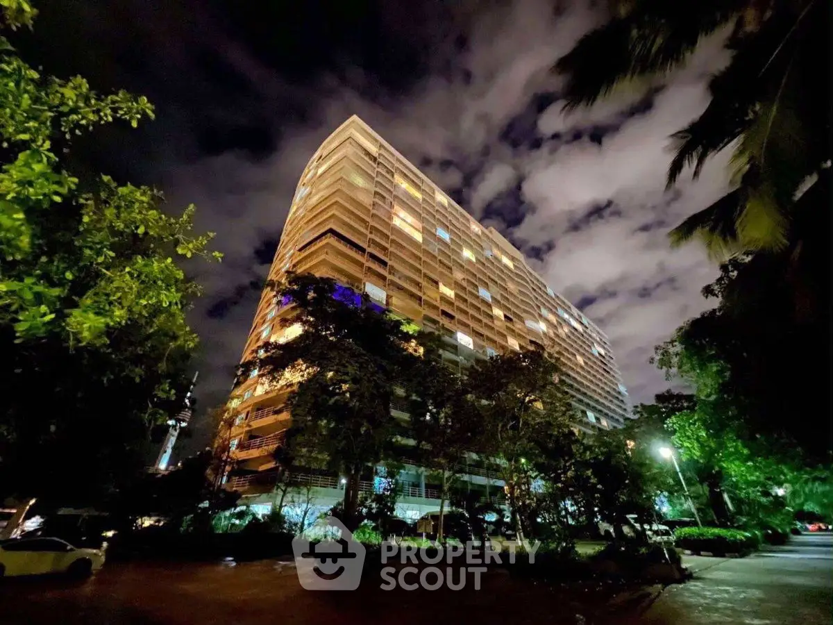 Stunning night view of a modern high-rise building surrounded by lush greenery.