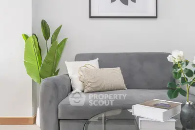 Modern living room with stylish gray sofa, decorative pillows, and lush green plant for a cozy ambiance.