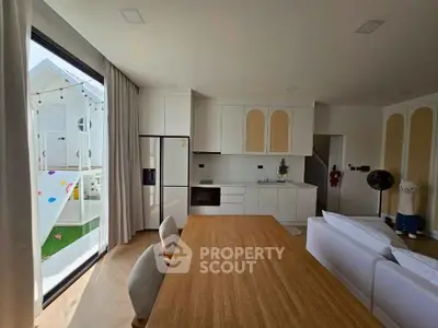 Modern kitchen with open layout and stylish dining area, featuring large windows and contemporary design.