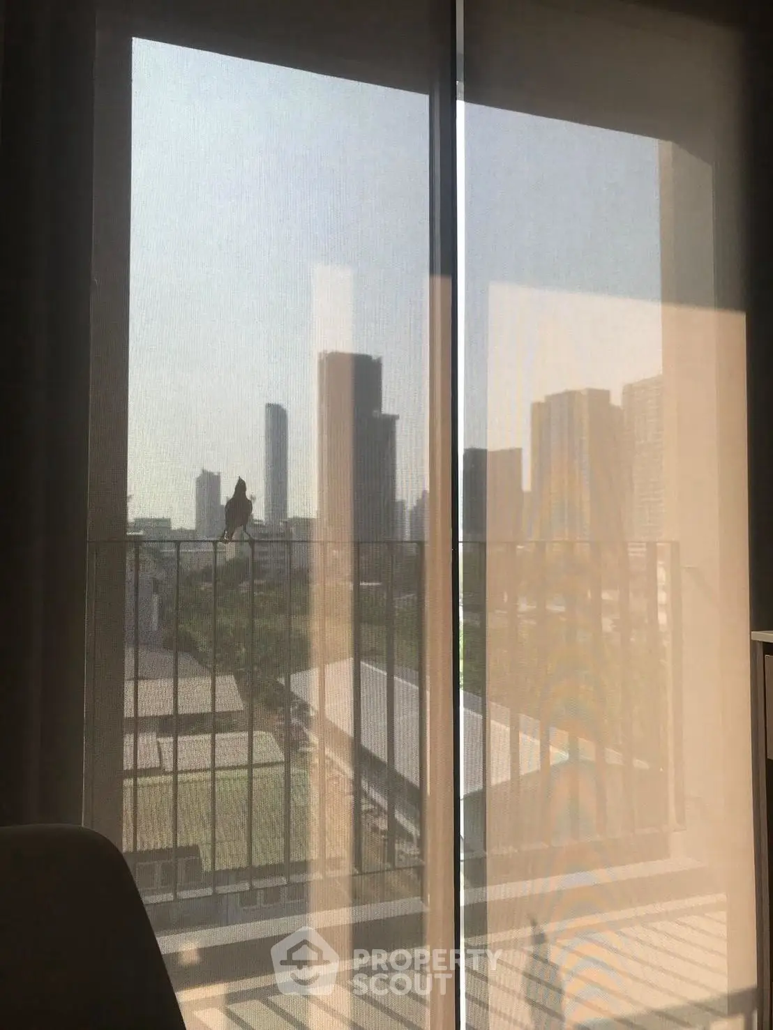 Modern city view from apartment balcony with glass railing and skyline.