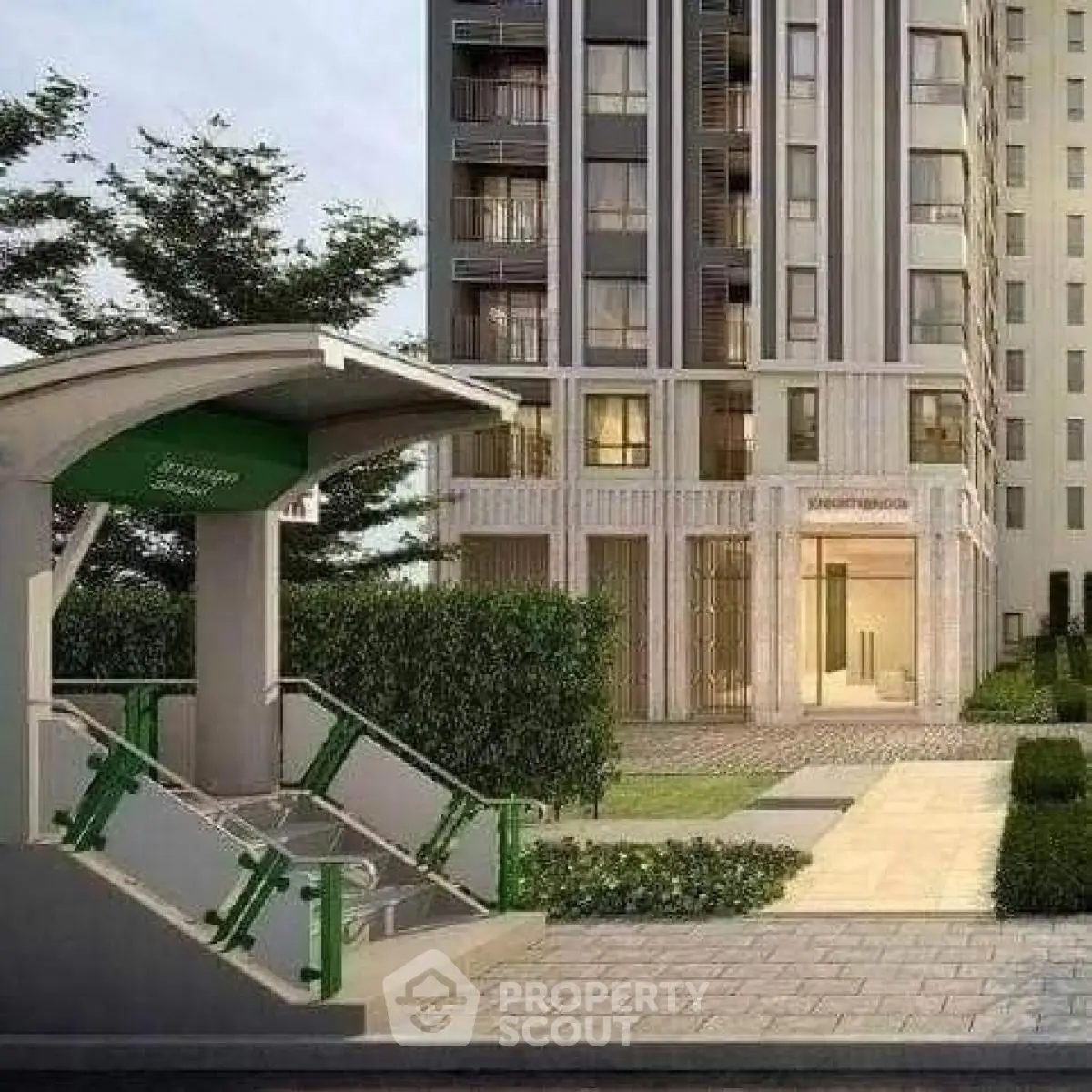 Modern apartment building entrance with lush landscaping and nearby subway access.