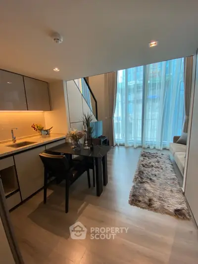 Modern living room with high ceilings and large windows, featuring a cozy dining area and stylish decor.