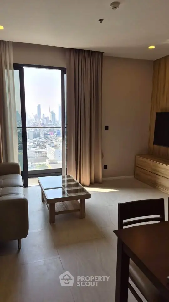 Modern living room with city view, featuring sleek furniture and floor-to-ceiling windows.