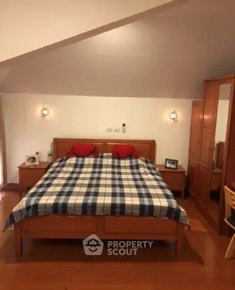 Cozy bedroom with wooden furniture and checkered bedding in a stylish home.