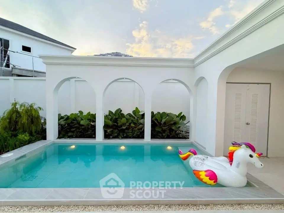 Luxurious private pool with elegant arches and unicorn float in serene setting