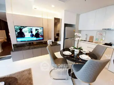 Modern open-layout kitchen and living area with sleek furniture and large TV