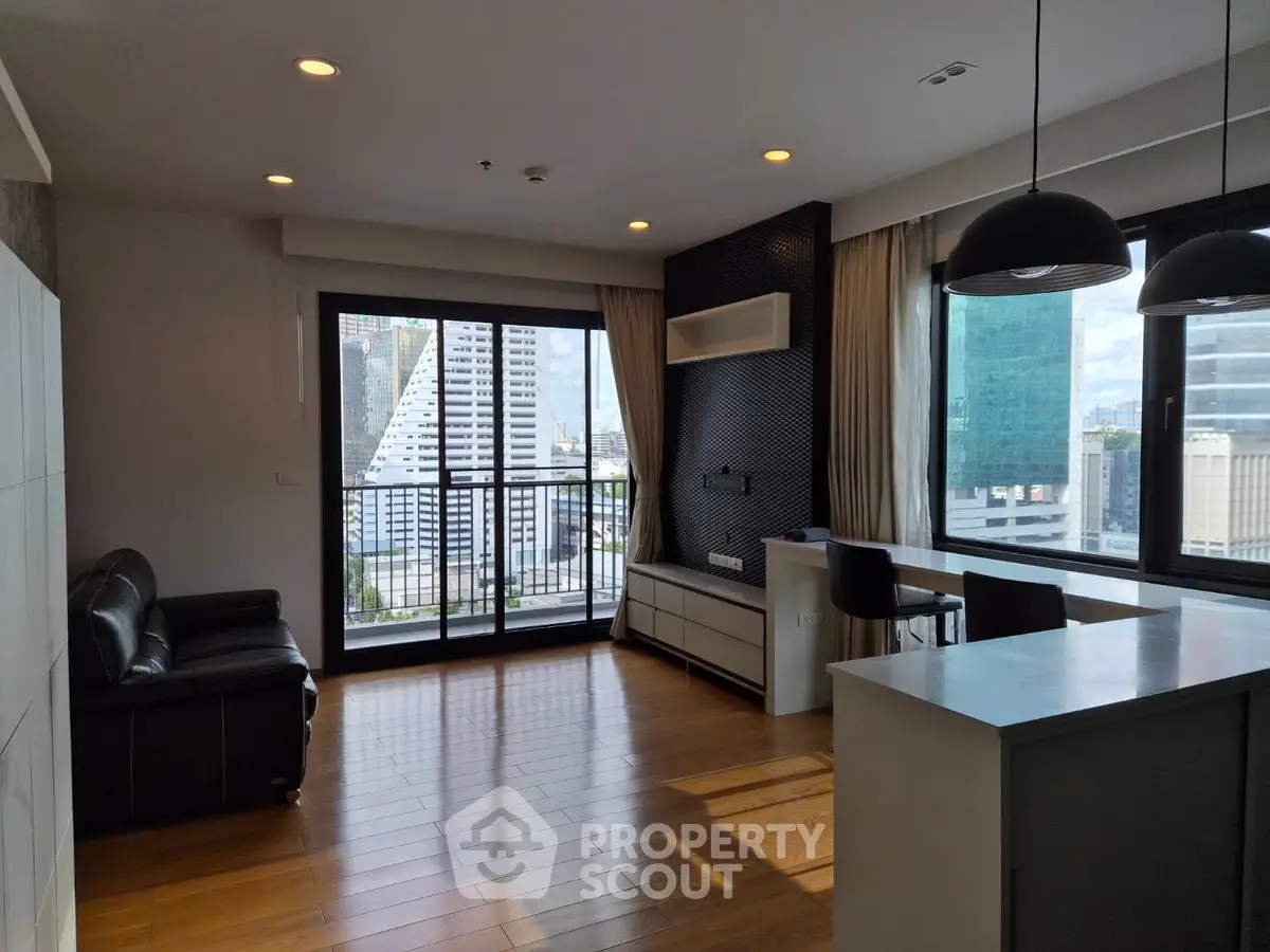 Modern living room with city view, featuring sleek furniture and large windows for natural light.