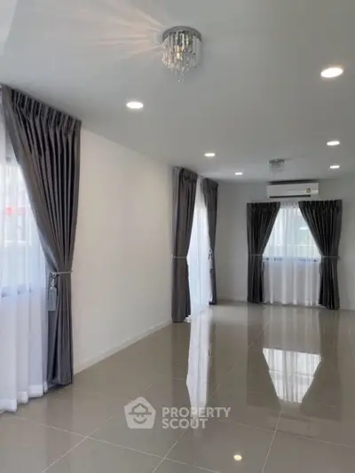 Spacious living room with elegant curtains and modern lighting, perfect for stylish living.