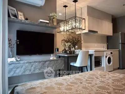 Modern open-layout living room with kitchen, featuring elegant chandelier and built-in appliances.