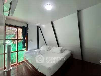 Cozy bedroom with modern design and large window offering natural light.