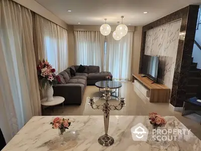 Luxurious living room with elegant marble flooring, plush grey sofa set, and modern lighting fixtures, complemented by chic decor and a sophisticated ambiance.