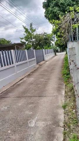 Quiet residential alley with white fence and lush greenery