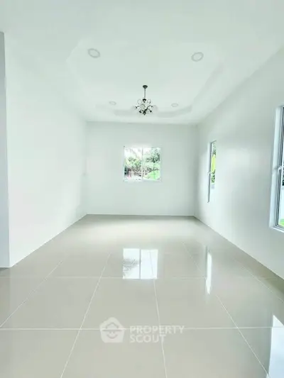 Spacious empty room with glossy tiled floor and elegant ceiling light fixture.