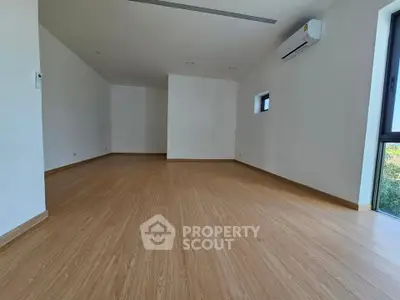 Spacious modern room with wooden flooring and natural light, perfect for versatile living space.