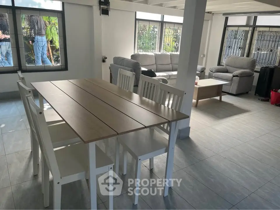 Spacious living and dining area with modern furniture and large windows for natural light.
