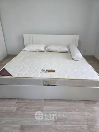 Spacious bedroom with modern white bed and minimalist decor, perfect for relaxation and comfort.