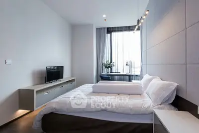 Modern bedroom with stylish decor and large window offering natural light.