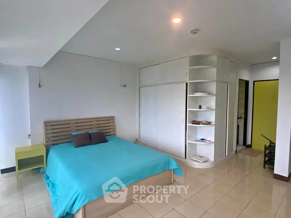 Spacious bedroom with modern design and ample storage in a bright apartment.
