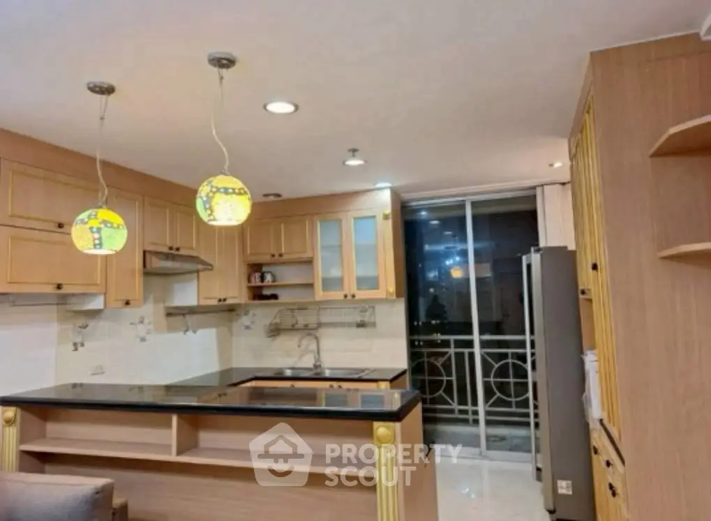 Spacious kitchen with modern lighting and open layout, featuring sleek countertops and ample storage.