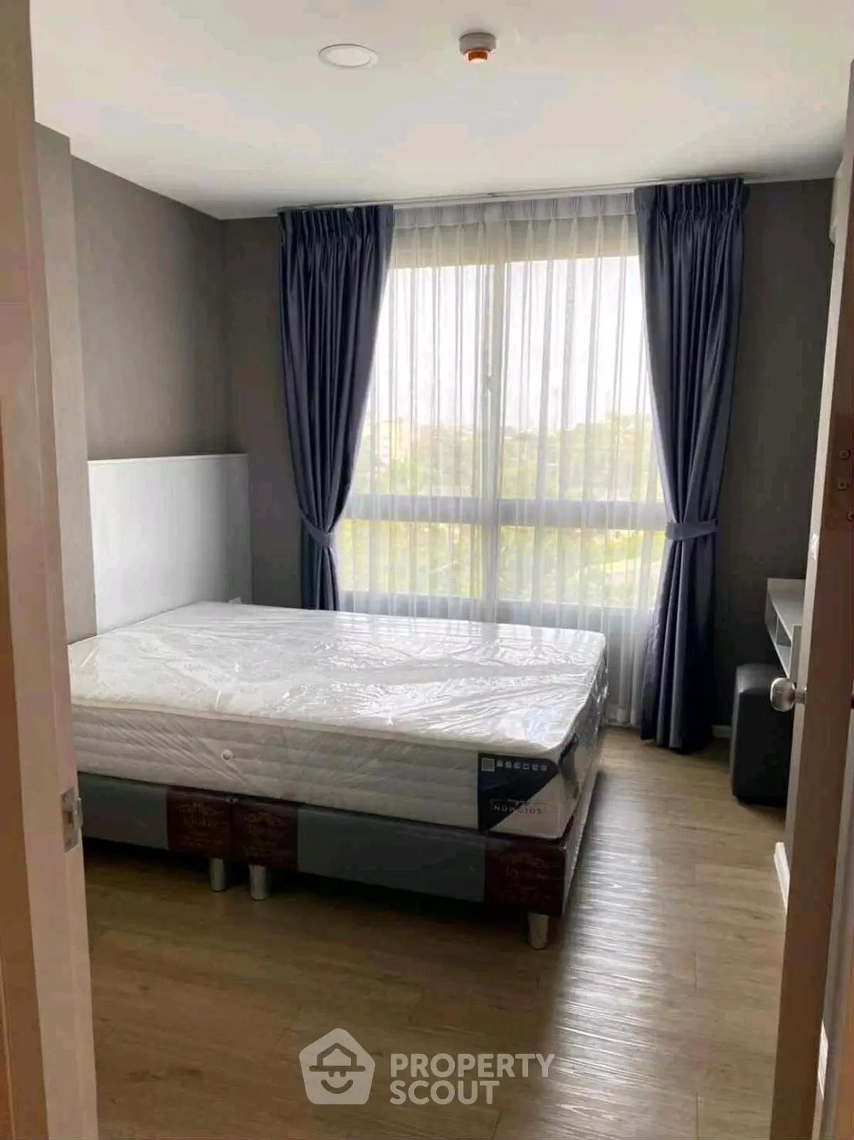 Cozy bedroom with large window and modern furnishings, perfect for relaxation.