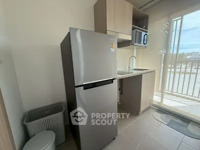 Modern kitchen with stainless steel fridge and microwave, ample natural light, and balcony view.