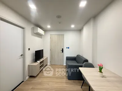 Modern living room with sleek furniture and wooden flooring, featuring a cozy sofa and flat-screen TV.