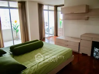 Spacious bedroom with balcony access and modern furnishings in a bright apartment.