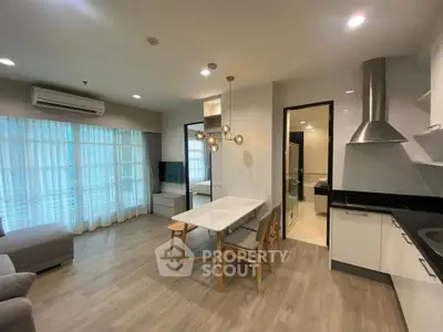 Modern open-layout kitchen and dining area with stylish lighting and large windows.
