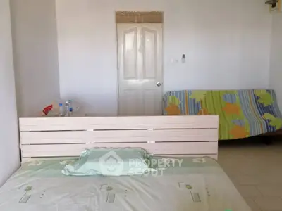 Cozy bedroom with minimalist decor and colorful sofa, perfect for relaxation.