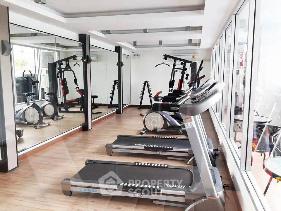 Modern gym with treadmills and fitness equipment in bright room with mirrors