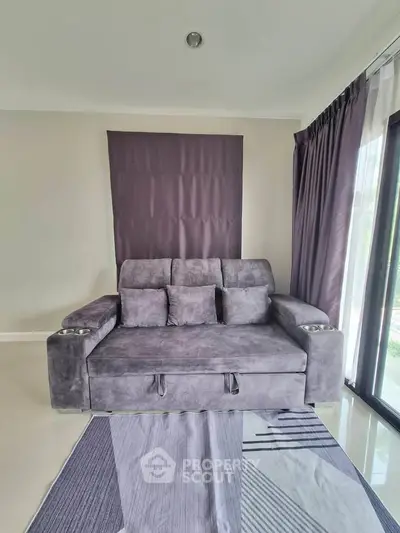 Modern living room with stylish gray sofa and floor-to-ceiling windows, offering a cozy and inviting atmosphere.