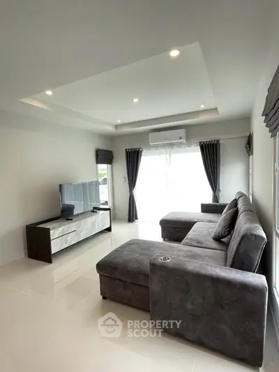 Spacious modern living room with plush gray sectional sofa and sleek entertainment unit, perfect for relaxation.