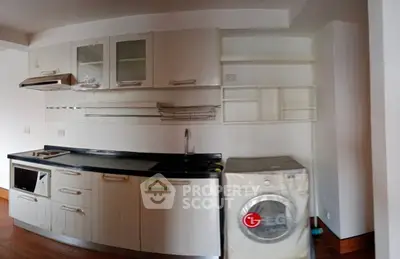 Modern kitchen with sleek cabinets and built-in appliances, featuring a washing machine.