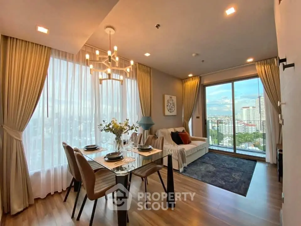 Elegant living room with city view, modern decor, and dining area in a high-rise apartment.
