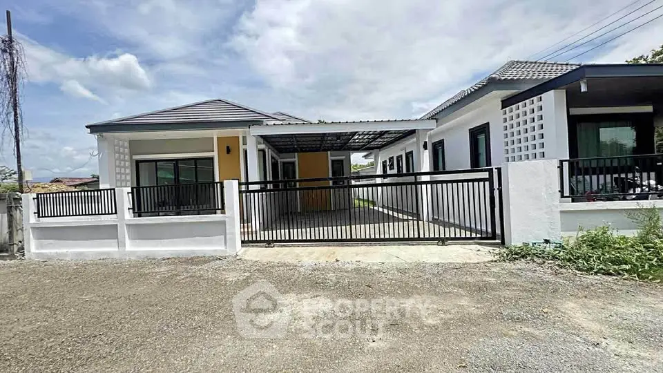 Modern single-story house with gated driveway and contemporary design.
