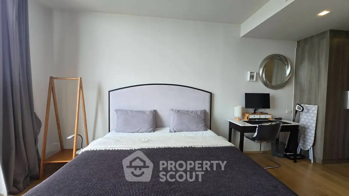 Modern bedroom with stylish decor and workspace, featuring a cozy bed and sleek furniture.