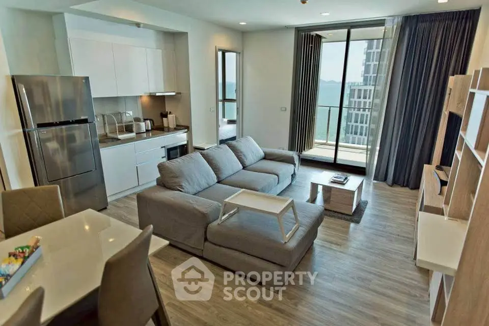 Modern open-plan living room with kitchen and balcony view in luxury apartment.