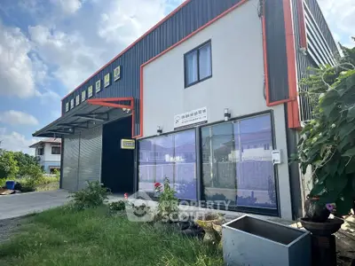 Modern industrial building with sleek design and spacious entrance, perfect for business operations.