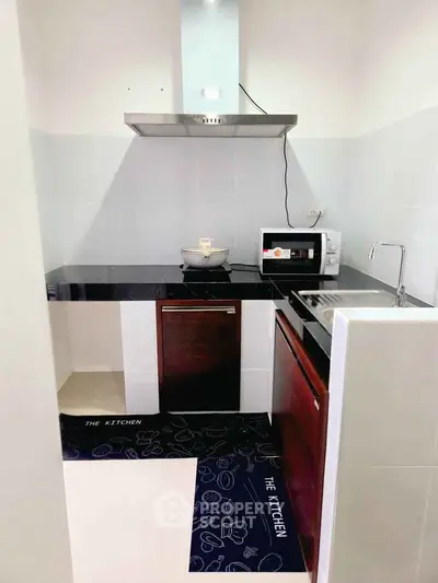 Modern compact kitchen with sleek appliances and black countertops.