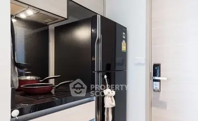 Modern kitchen with sleek black fridge and electric stove in compact apartment.