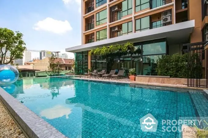 Luxurious residential building with a sparkling blue swimming pool surrounded by comfortable loungers, offering a serene urban oasis for relaxation and leisure.