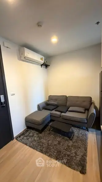 Cozy living room with modern gray sofa and air conditioning unit, perfect for relaxation.