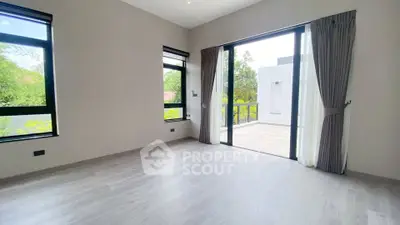 Spacious modern living room with large windows and balcony access, offering abundant natural light and serene views.